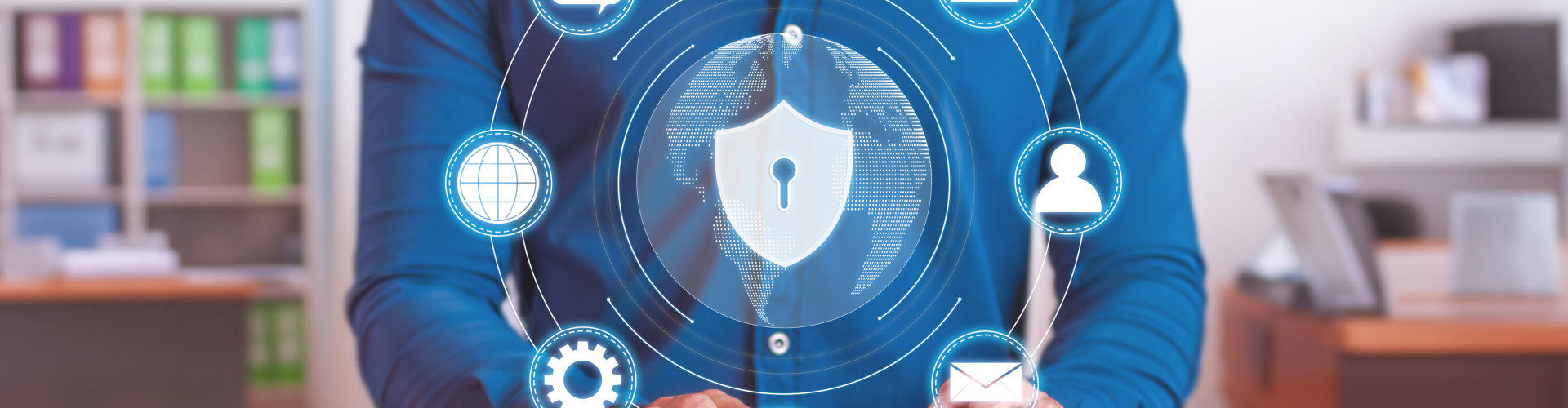 A person is shown from the torso up, typing on a computer keyboard at a brown wooden desk.